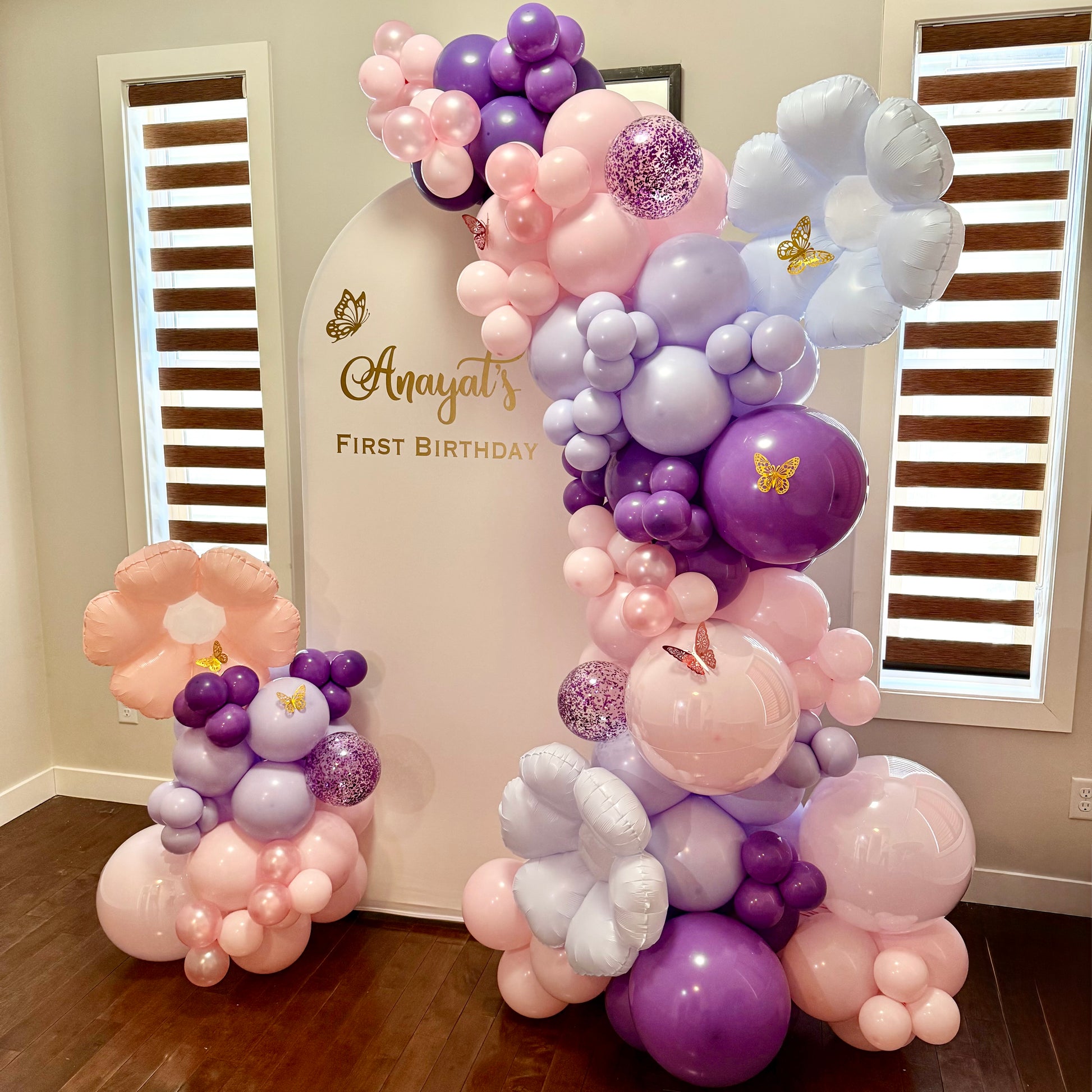 Balloon arch with Butterfly First Birthday theme  in a room 