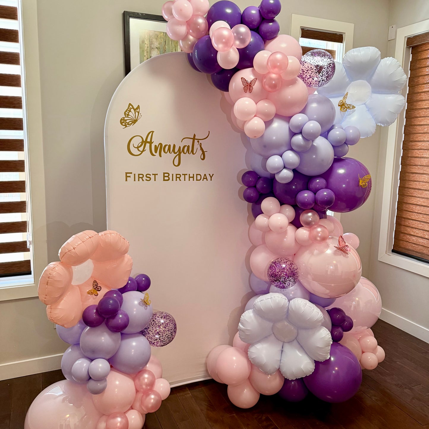 Balloon arch with 'the backdrop with custom 'First Birthday' text in enchanting style
